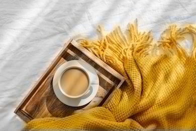 wooden tray with coffee and warm plaid on white bedding . breakfast in bed. hygge concept.