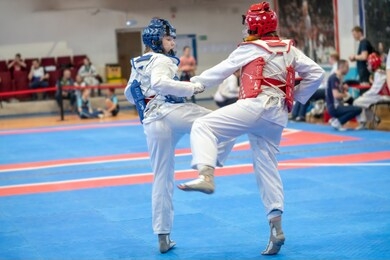  two girls in blue and red taekwondo equipment are fighting at doyang 
