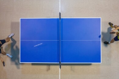 image of players playing on a blue tennis table, top view blurred motion