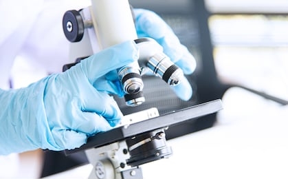 closed up asian woman scientist, researcher, technician, or student' hand conducting research or experiment by using microscope, the scientific equipment in medical, chemistry or biology laboratory