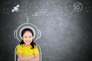 picture of confident schoolgirl smiling at the camera while imagining being an astronaut