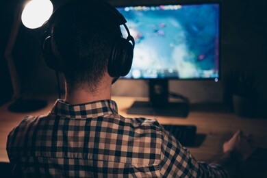 close up back rear behind view photo he him his guy play videogame battle challenge participation talk teammates headset microphone wear casual plaid checkered shirt internet table house indoors