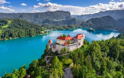 bled, slovenia - aerial panoramic view of beautiful bled castle (blejski grad) with lake bled (blejsko jezero), the church of the assumption of maria and julian alps at background on a nice summer day