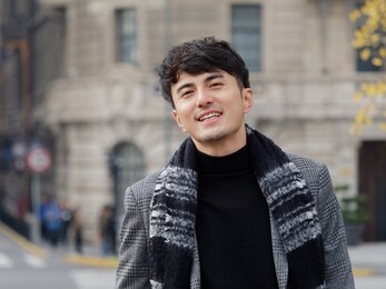 portrait of a handsome chinese young man in casual suit smiling and looking at camera confidently with shanghai bund background, winter fashion, cool young man lifestyle.