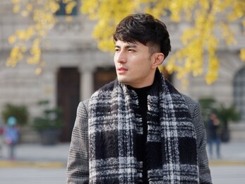 portrait of a handsome chinese young man in casual suit looking away with shanghai bund background, winter fashion, cool young man lifestyle.
