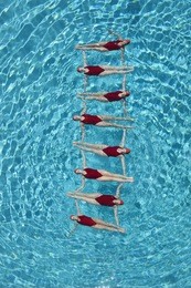 group of synchronised swimmers forming a ladder in pool