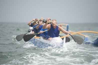 crew of a racing outrigger canoe on water