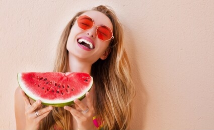 sexy girl in red sunglasses holds a cut watermelon in her hands. happy woman in trendy red sunglasses copy space