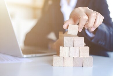 closeup picture of a businessman placing wooden blocks to represent the peak of the boom to grow their business goals, financial statistics.