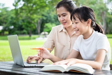 happy asian mother,daughter enjoying using laptop computer in outdoor park,female tutor or teacher working,teaching child girl how to learning,student is interested in studying having fun,(education) 