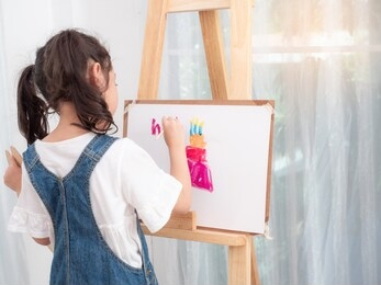 little asian cute girl 6 years old playing watercolors painting cake for happy birthday on white paper. learning and education of kid.