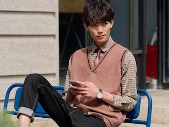 portrait of a handsome chinese young man with korean style clothes sitting and looking away with mobile phone in hand, male fashion, cool asian young man lifestyle.