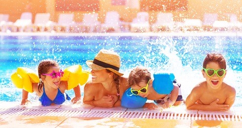 happy family in the pool, having fun in the water, mother with three kids enjoying aqua park, beach resort, summer holidays, vacation concept 