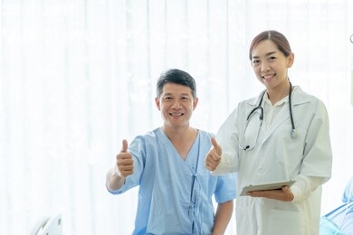 asian senior patient on hospital bed discussing with female doctor - selective focus point