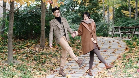 portrait of happy chinese young lover hands in hands and dancing in autumn forest park, romantic lover concept.