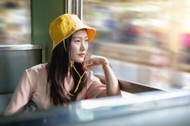 young beautiful asian woman sitting on the train seat and looking through the train window.