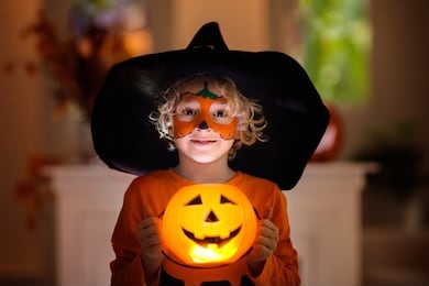 child in halloween costume. kids trick or treat. little boy with pumpkin face painting and lantern.