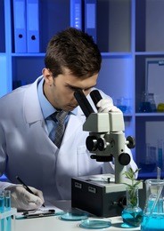 young laboratory scientist looking at microscope in lab