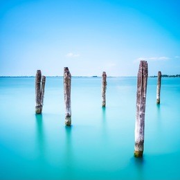 poles and soft water on venice lagoon. long exposure photography.