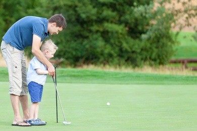 handsome father and his cute son playing golf together