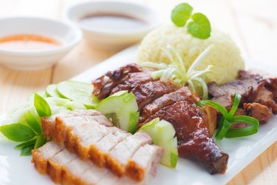 roasted duck, roasted pork crispy siu yuk and charsiu chinese style, served with steamed rice on dining table. singapore cuisine.