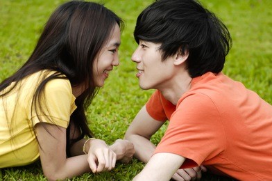 young couple laying on park lawn