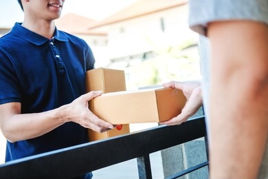 delivery asian man service with boxes in hands standing in front of customer's house doors