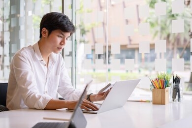 portrait of a serious asian businessman thinking and concentrating typing on laptop at co-working spaces. man laptop working concept