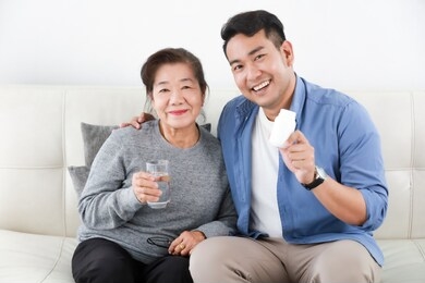 asian senior woman mother with young man son with medicine and grass of water in living room