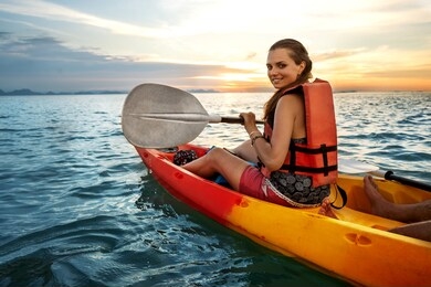 couple kayaking together. beautiful young couple kayaking on lake together and smiling at sunset