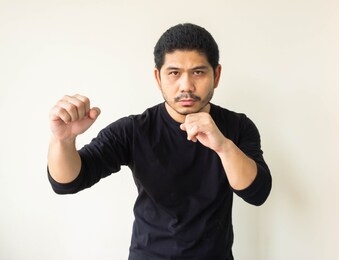 asian man doing fighting stance. young man with box stance ready to fight. aggressive young man with a goatee standing in a fight stance, fists raised, strong and confident.