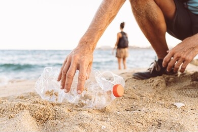 man picking up plastic bottle that pollute the sea, cleaning on the beach, campaign to clean volunteer concept