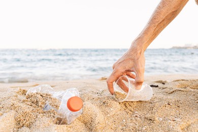 man picking up plastic bottle that pollute the sea, cleaning on the beach, campaign to clean volunteer concept
