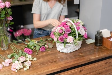 handsome fresh bouquet. flowers delivery. woman florist create flower arrangement in a wicker basket. beautiful bouquet of mixed flowers. floral shop concept .