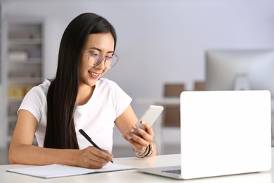 young asian student using mobile phone while preparing for exam