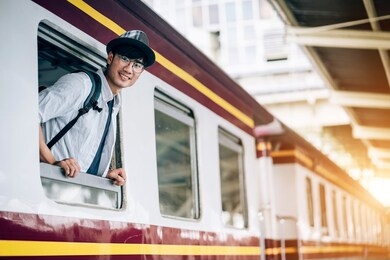 asian man is traveler, he is waiting for their train. outdoor adventure travel by train concept. bangkok, thailand. happy/positive/healthy hike/travel/wanderlust concept