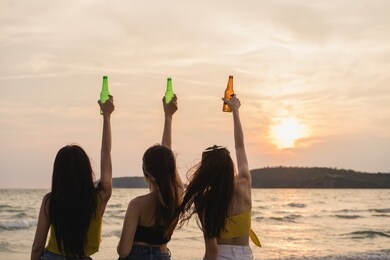 group of asian teenage girls having party celebrating on beach, friends happy drinking beer on beach at sea when sunset in evening. outdoor activity friends travel holiday vacation summer concept.