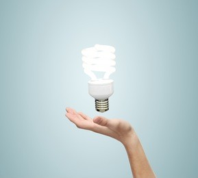 hand and energy saving lamp on a blue background