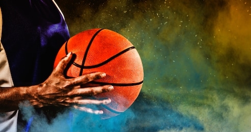 tough female basketball player against splashing of yellow color powder