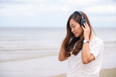 a sad woman listening to music with headphone by the sea