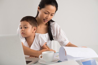 mother sitting with her child and working at the same time