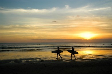 surfer walking at sunset