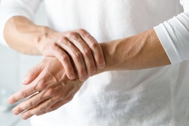 closeup of male arms holding her painful wrist caused by prolonged work on the computer, laptop. carpal tunnel syndrome, arthritis, neurological disease concept. numbness of the hand