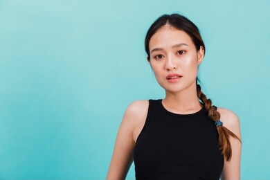 portrait of confident beautiful asian fitness woman standing after exercise isolated on blue color background with copy space.concept of slim and healthy happy girl workout.