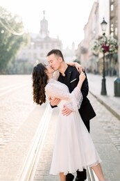 passionate hugs and kiss of asian couple newlyweds on the street of old city, beautiful buildings on the background