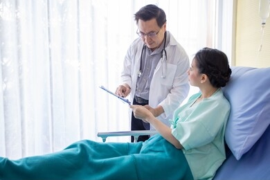 the doctors are asking and explaining about the illness to a female patient lying in bed at a hospital.