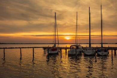 golden and bronze magic sunset with a wonderful view of the sun and clouds on the beach pier with luxury yachts and with pleasant reflections on the sea water.