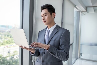 successful man with laptop in modern white office with glass around