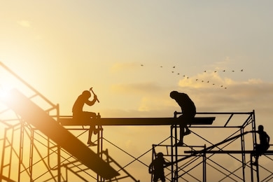 silhouette of worker on building site, construction site at sunset in evening time.