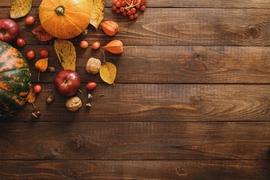 autumn composition. pumpkins, fallen leaves, apples, red berries, walnuts on wooden table. happy thanksgiving concept. flat lay, top view, copy space